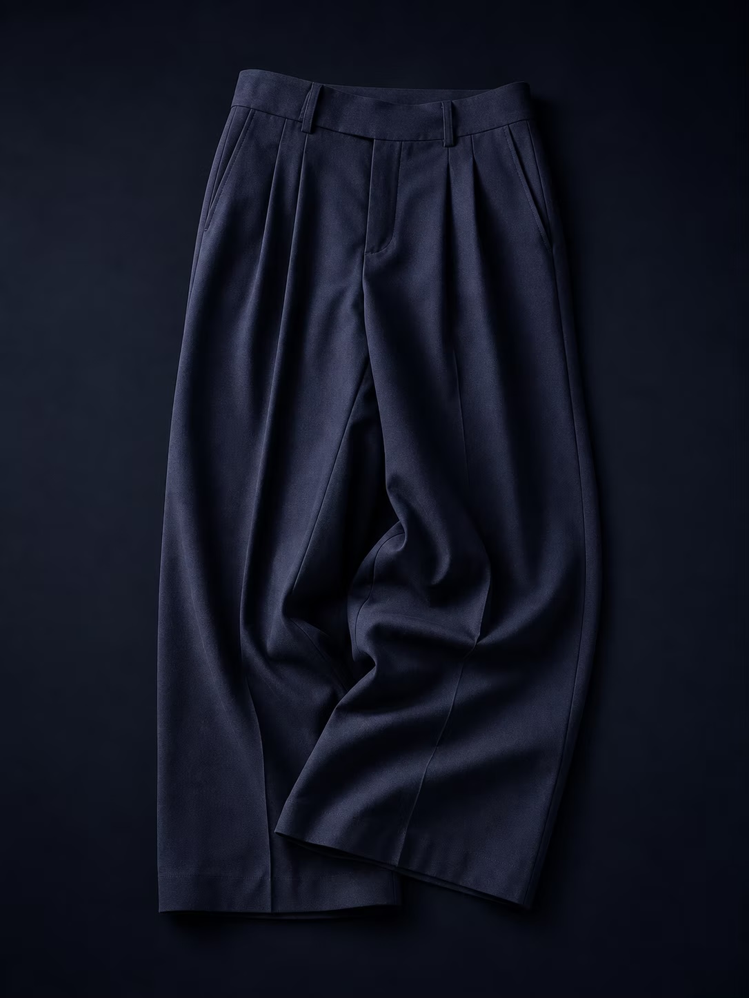 Midnight-navy tailored trousers photographed on a dark background.